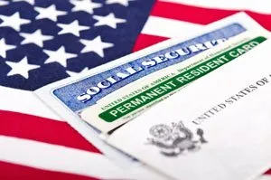 Green card (tarjeta de residencia permanente) y tarjeta de Seguro Social sobre la bandera de Estados Unidos